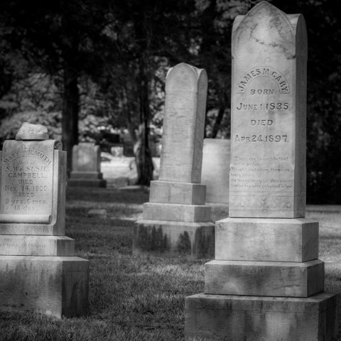Black and white image of old tombstones in a cemetery.